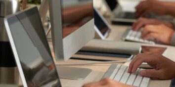 Hands using a keyboard on a desktop computer and a laptop