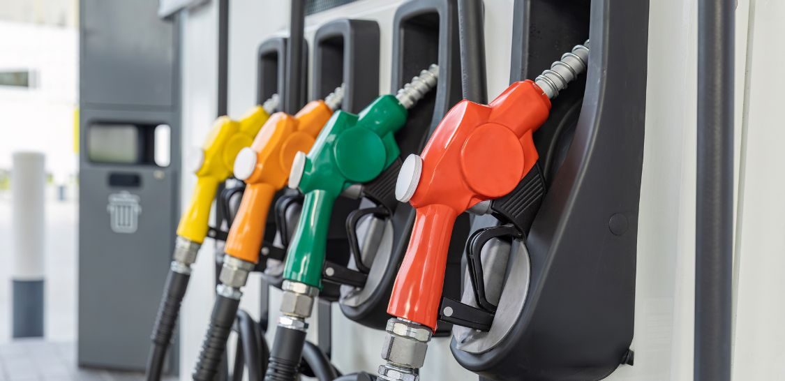 a row of gas pumps of various colors including red, green, orange, and yellow