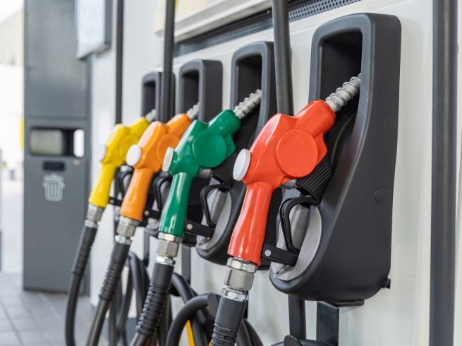 a row of gas pumps of various colors including red, green, orange, and yellow