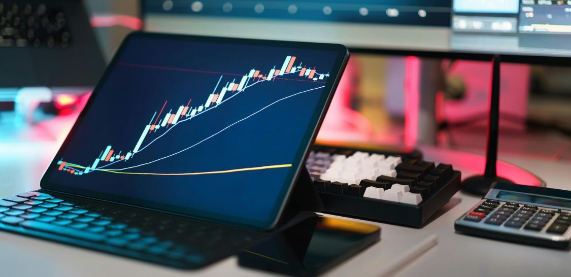 A computer screen with stock market graph sits on a desk