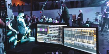 Musicians playing for a crowd and sound equipment displaying stats on screens.