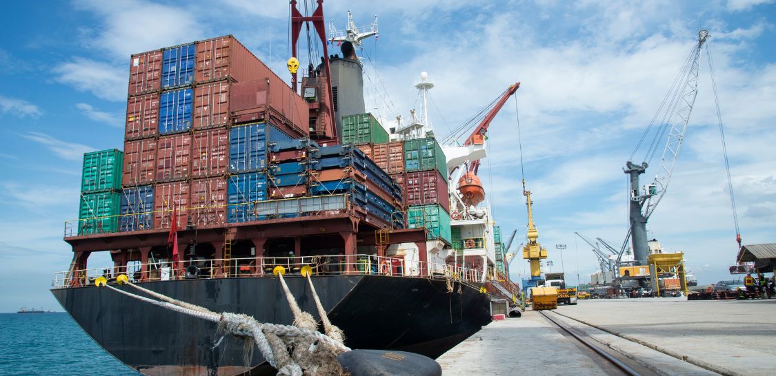 A barged full of shipping containers sits at a dock