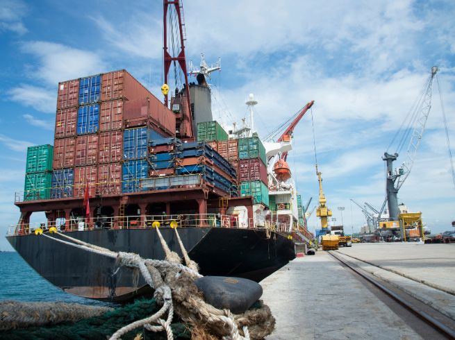 A barged full of shipping containers sits at a dock