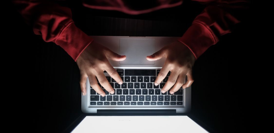 an overview image of a person wearing a read long sleeve shirt typing on a laptop