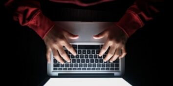 an overview image of a person wearing a read long sleeve shirt typing on a laptop