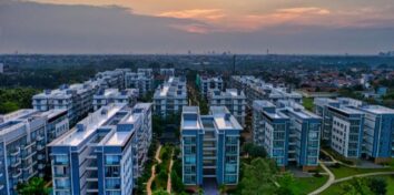 A group of apartment builds with green space and a sunset in the background