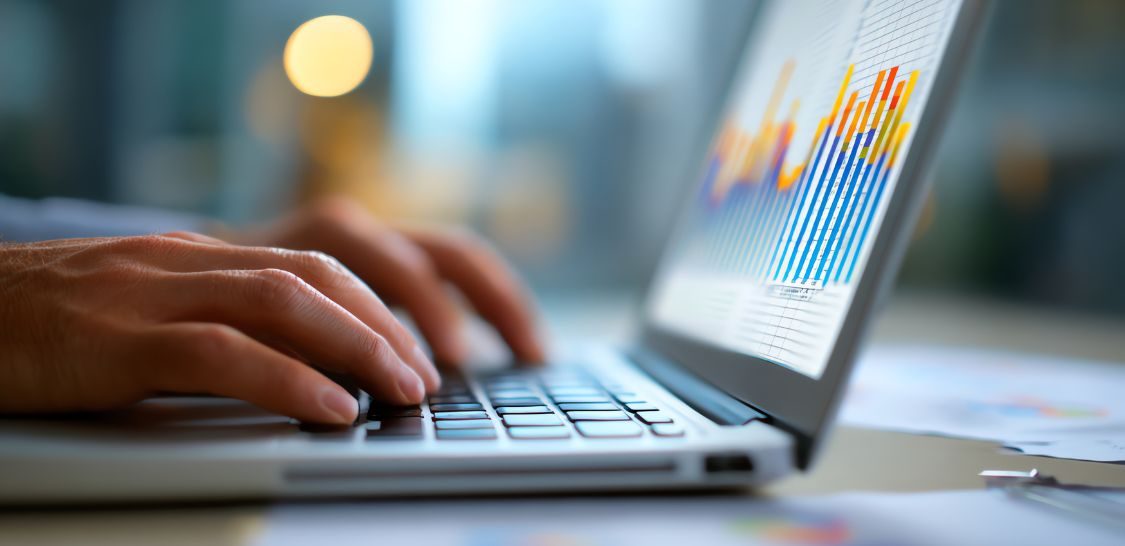 A pair of hands types on a laptop keyboard with a graph on the screen