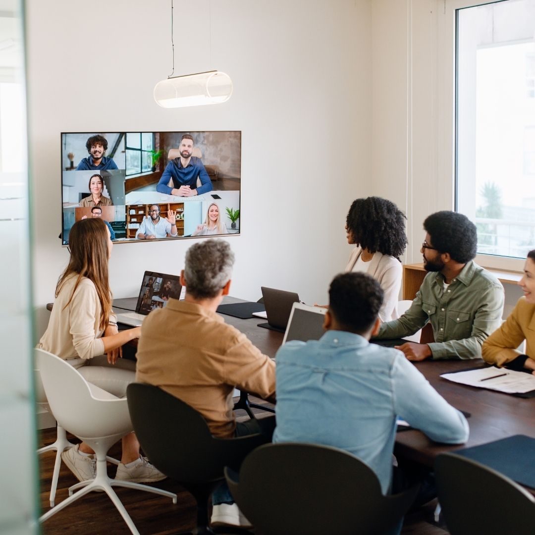 Office team collaborating in person while connecting with remote participants by video.