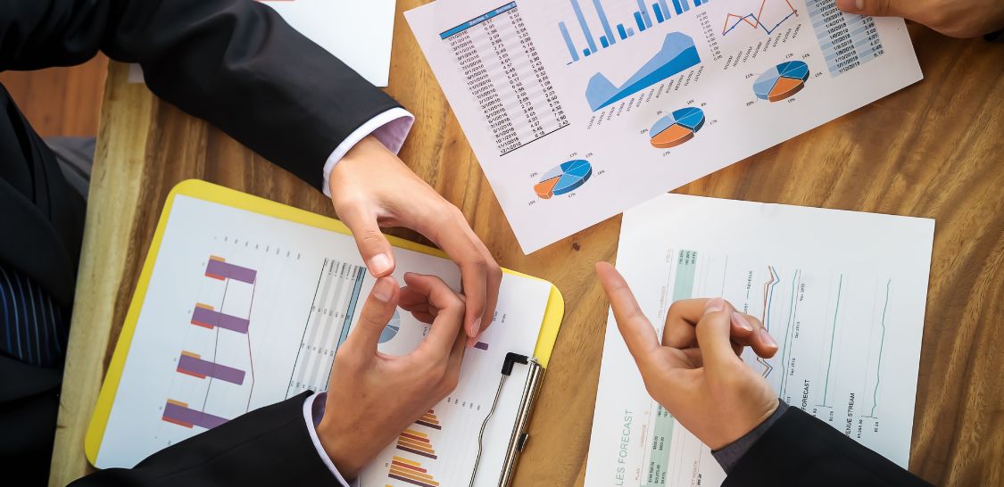 An overhead photo of two sets of hands over a table that has financial documents on it
