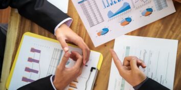 An overhead photo of two sets of hands over a table that has financial documents on it