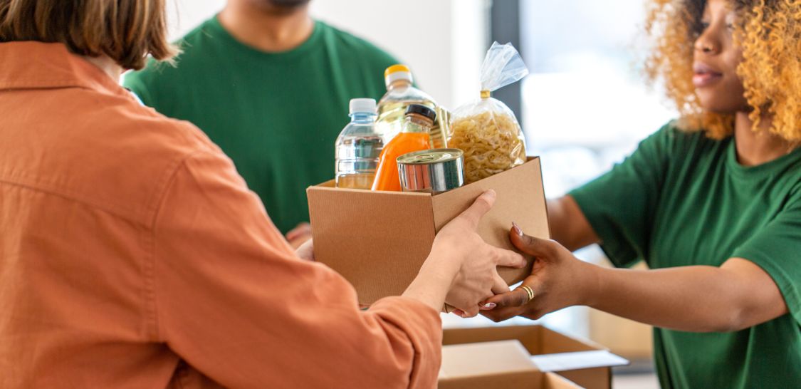 a person hands a box of food and drinks to another person at a nonprofit organization