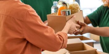a person hands a box of food and drinks to another person at a nonprofit organization