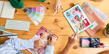 A photo from overhead of people around a table looking at paint swatches and fashion designs on a tablet