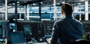 Cybersecurity professional monitors multiple screens displaying network data and security analytics in a modern operations center.